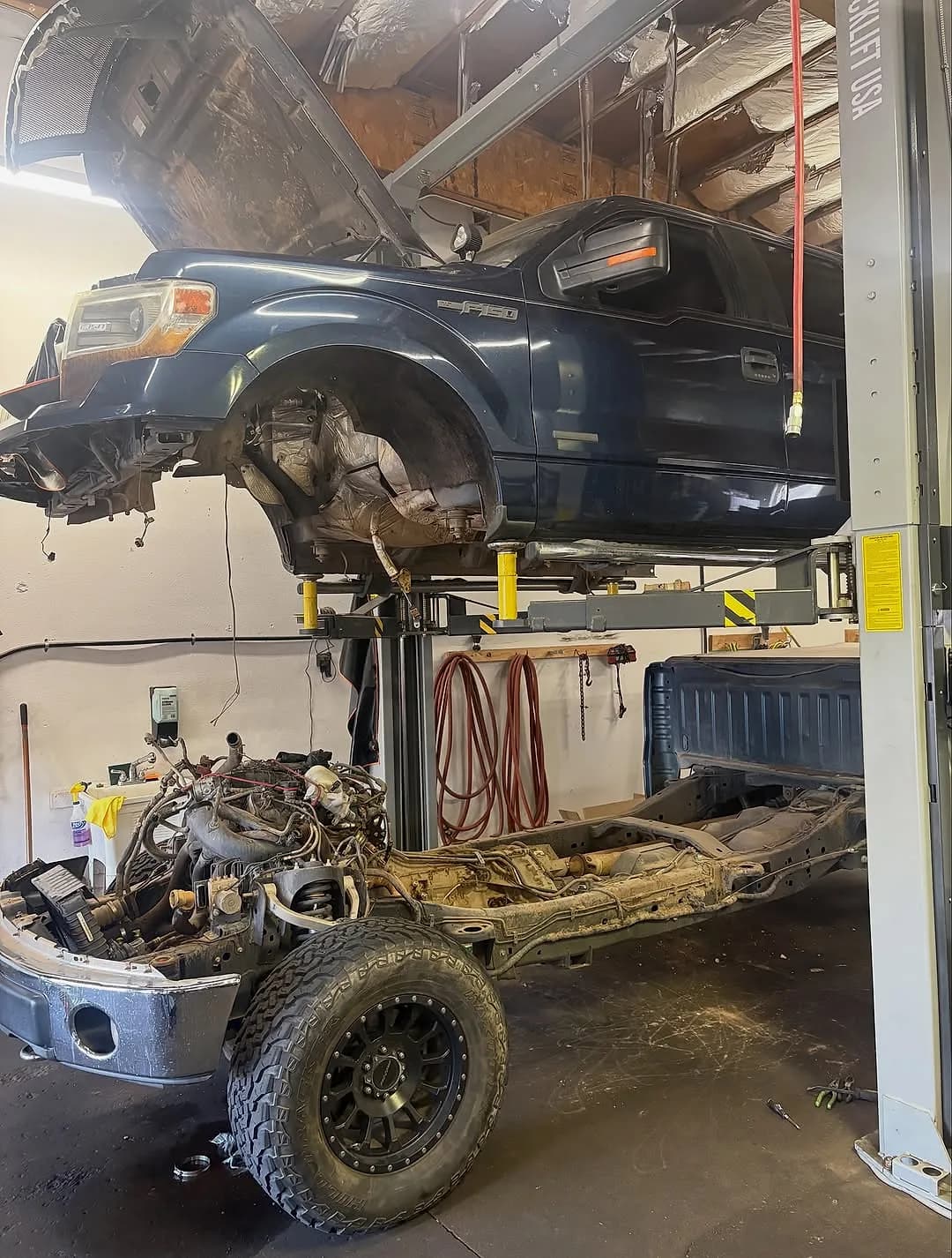 A Ford F-150 with its cab lifted off and the frame lowered to reach the exhaust manifolds at Mesa Auto & Fleet