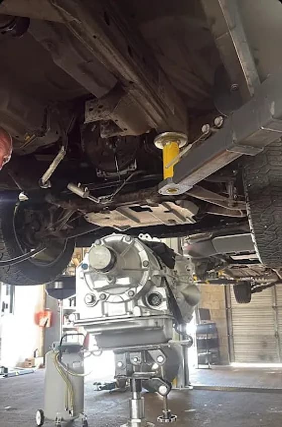 A transmission on a transmission jack being fitted under a truck on the lift at Mesa Auto & Fleet